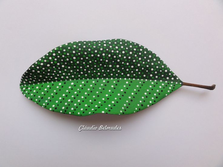 a green leaf with white polka dots on it is laying on a table next to a brown stick