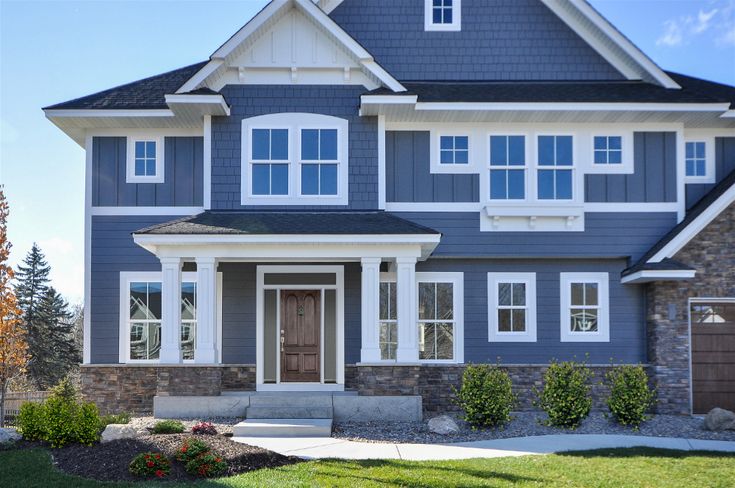 a large blue house with white trim and lots of windows on the front door is shown