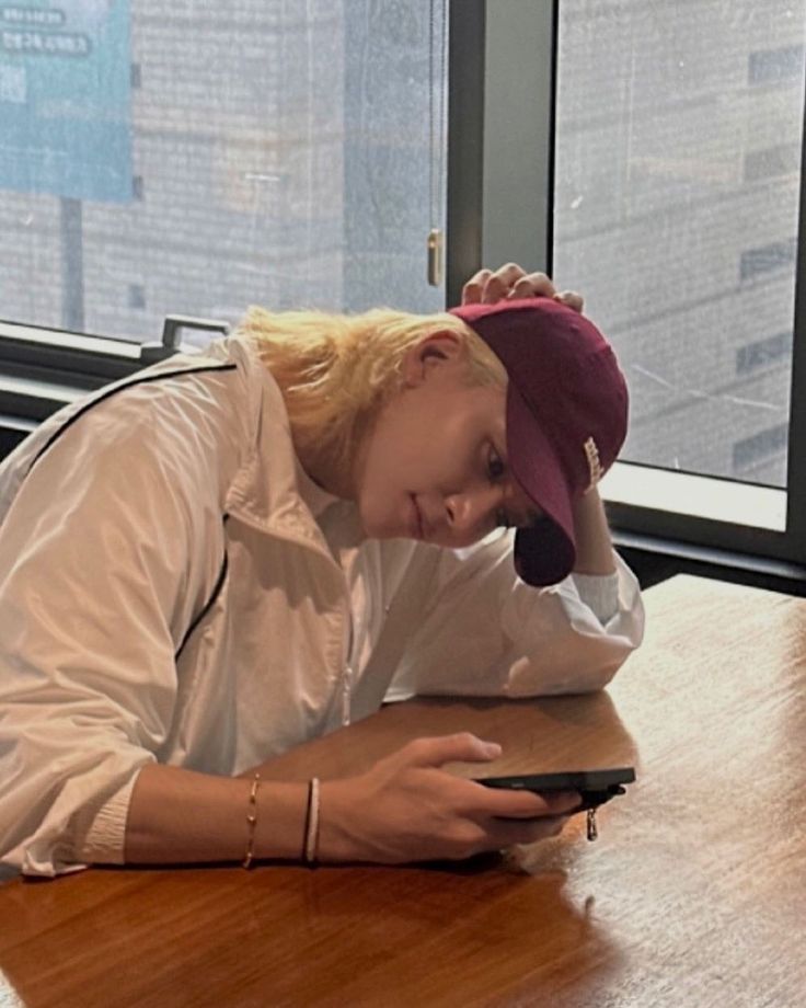 a woman sitting at a table with a cell phone in her hand and looking down