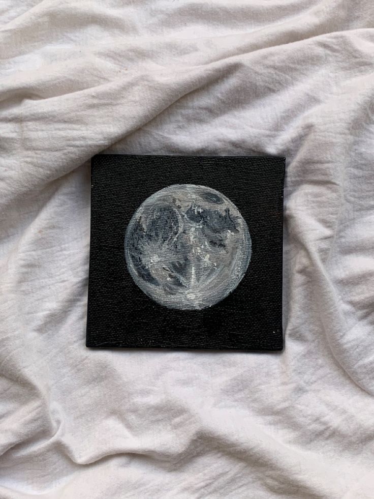 a black and white photo of the moon on top of a white bed linens