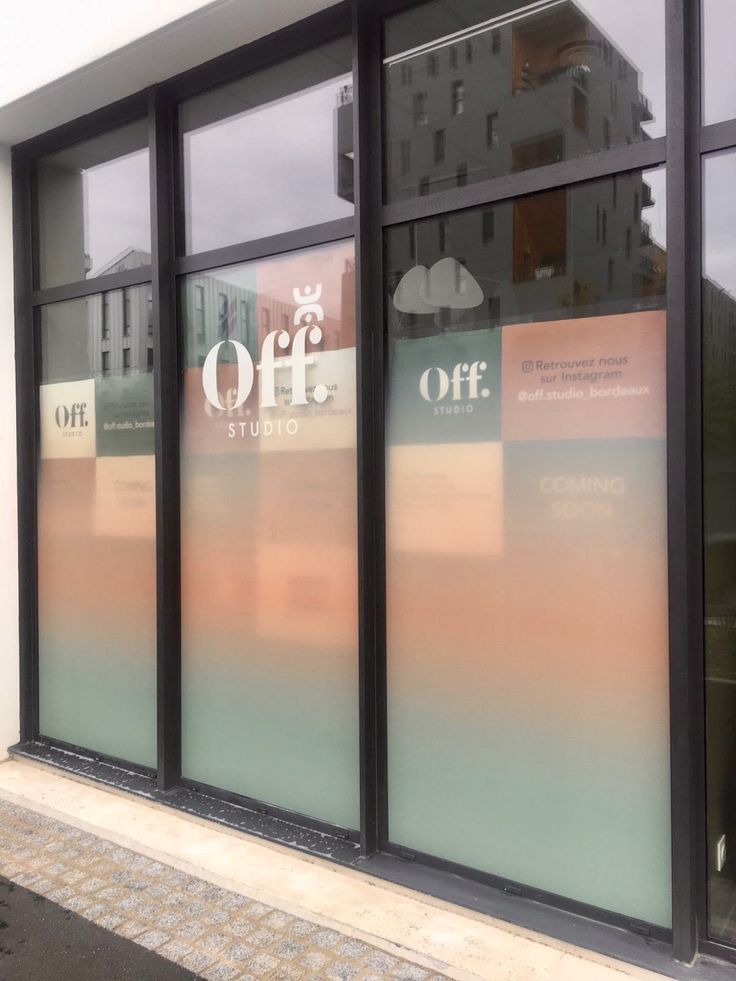 the front window of a building with large glass windows on each side and an off sign