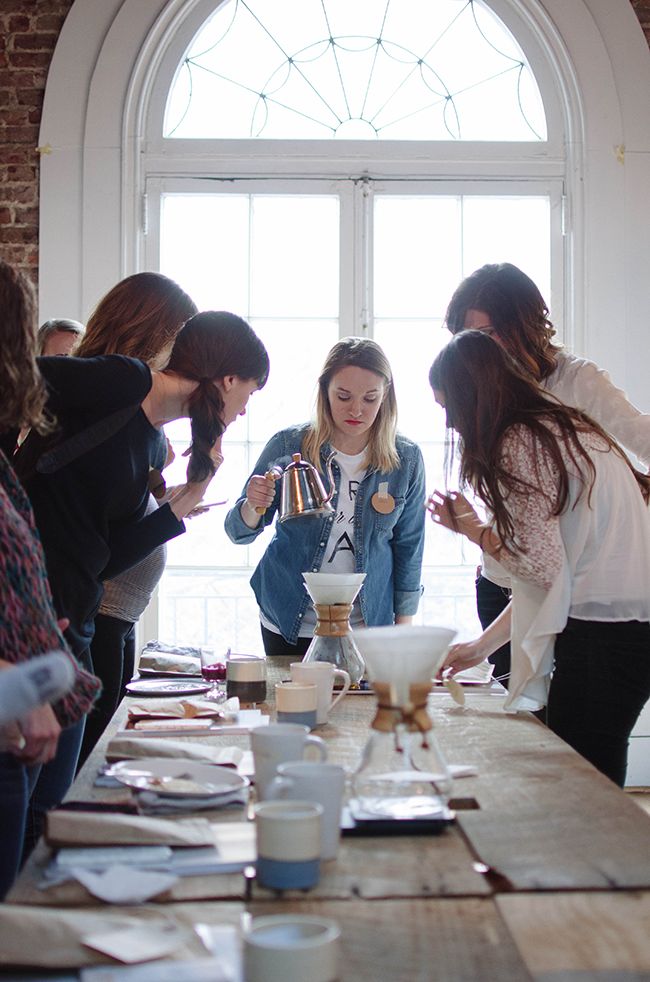 a group of women standing around a table with plates and cups on top of it