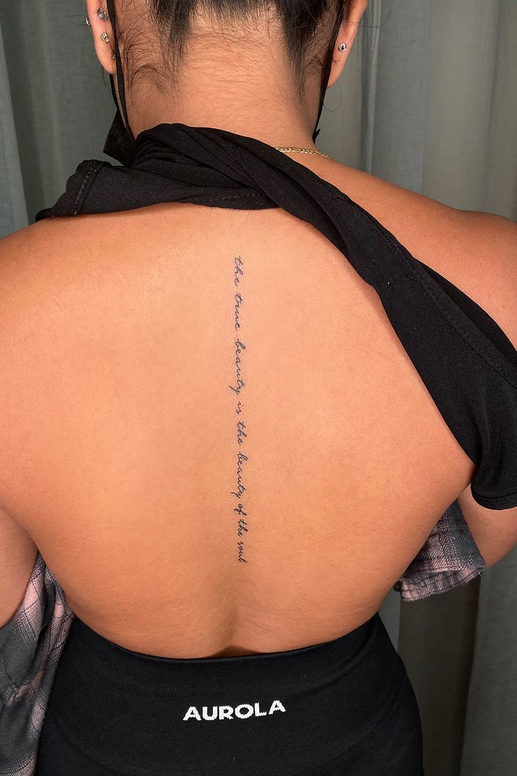 the back of a woman's upper body with writing on her left shoulder and right arm