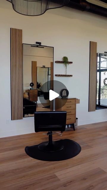 a hair salon with chairs and mirrors on the wall, in front of two windows