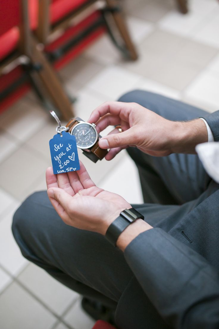 a person sitting on the floor holding a small clock in their hand with an i love you tag attached to it