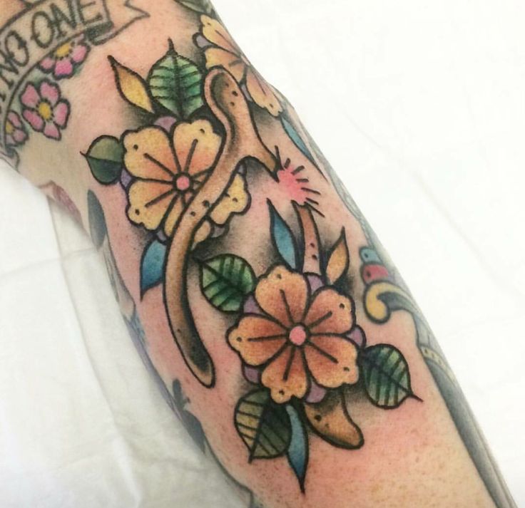 an arm tattoo with flowers and vines on it