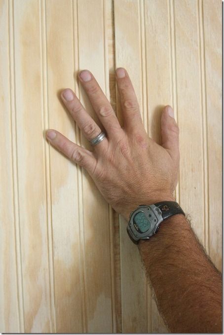 a man's hand on top of a wooden door with a watch on it