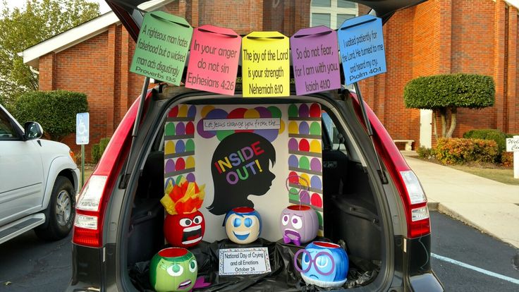 the back end of a car with decorations on it's trunk and door, in front of a brick building