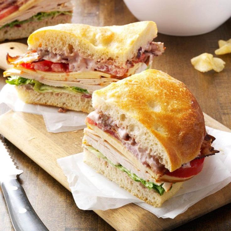 two sandwiches cut in half sitting on top of a cutting board