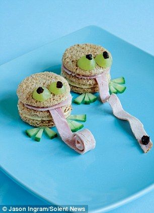 two sandwiches made to look like fish and vegetables are on a blue plate with a pink ribbon