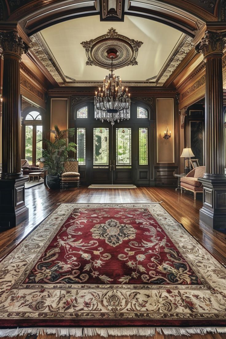 an ornate entry way with chandelier and red rug on the floor in front of it