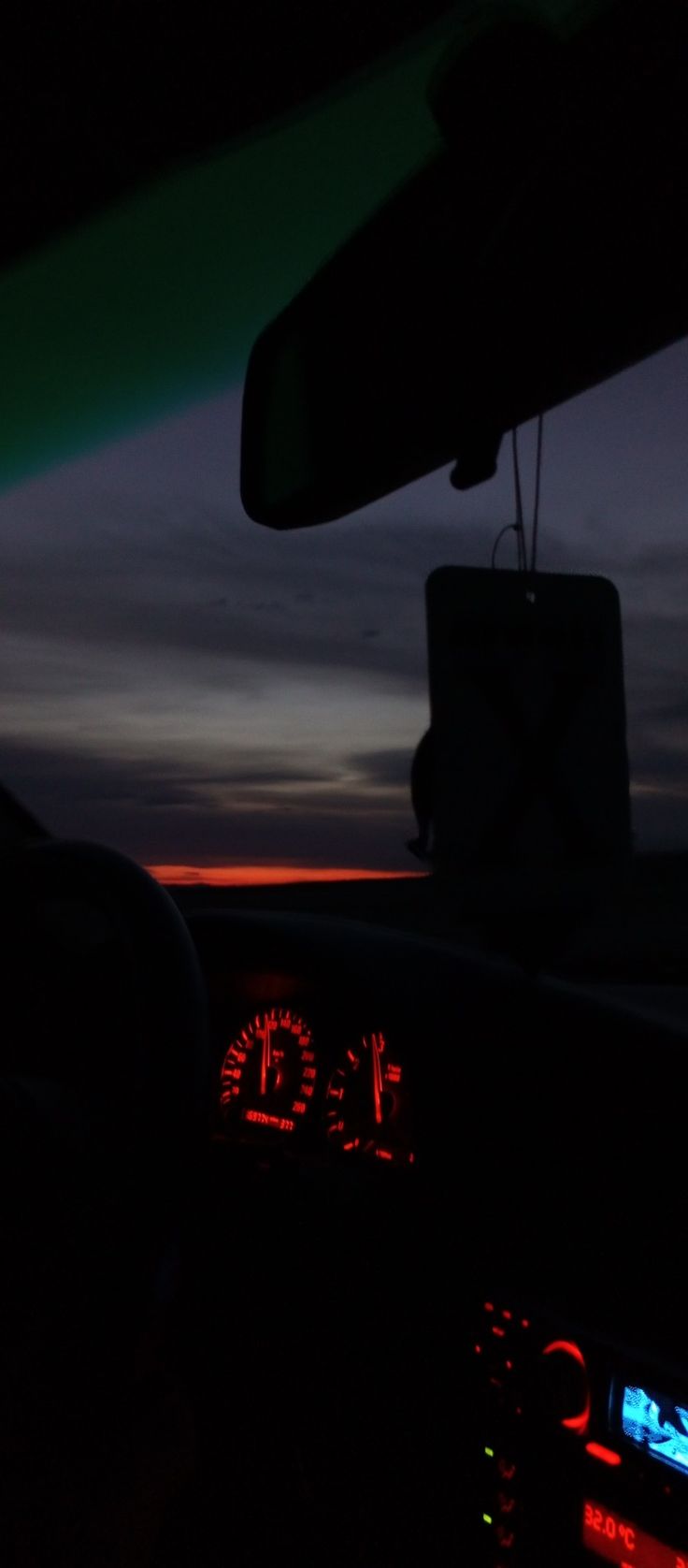 the sun is setting in the distance as seen from inside a vehicle's dashboard