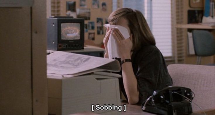 a woman sitting at a desk in front of a computer monitor with her hand on her face