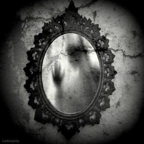 the reflection of a woman's torso in a circular mirror on a cracked wall