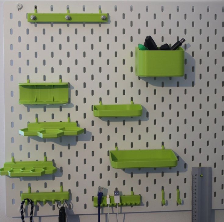 there are many green shelfs on the wall with scissors and other items in them