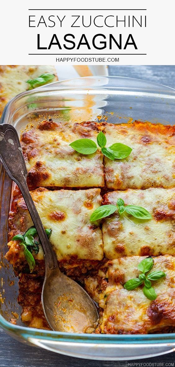 lasagna casserole with basil and cheese in a glass dish on a wooden table