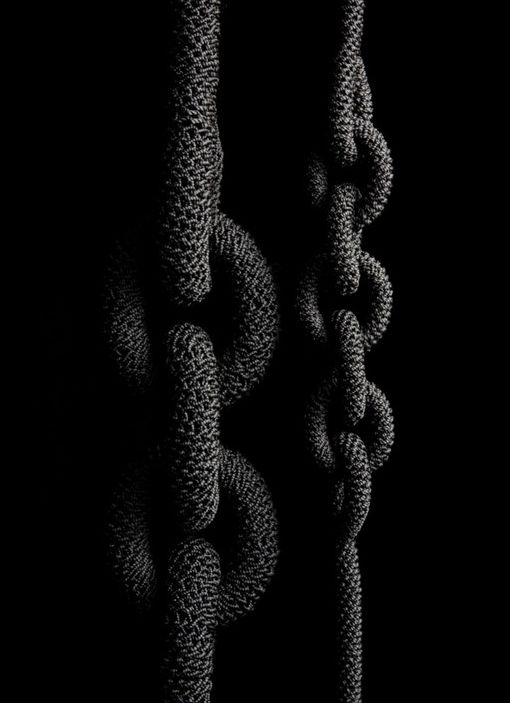 black and white photograph of ropes in the dark with one knot hanging from it's end