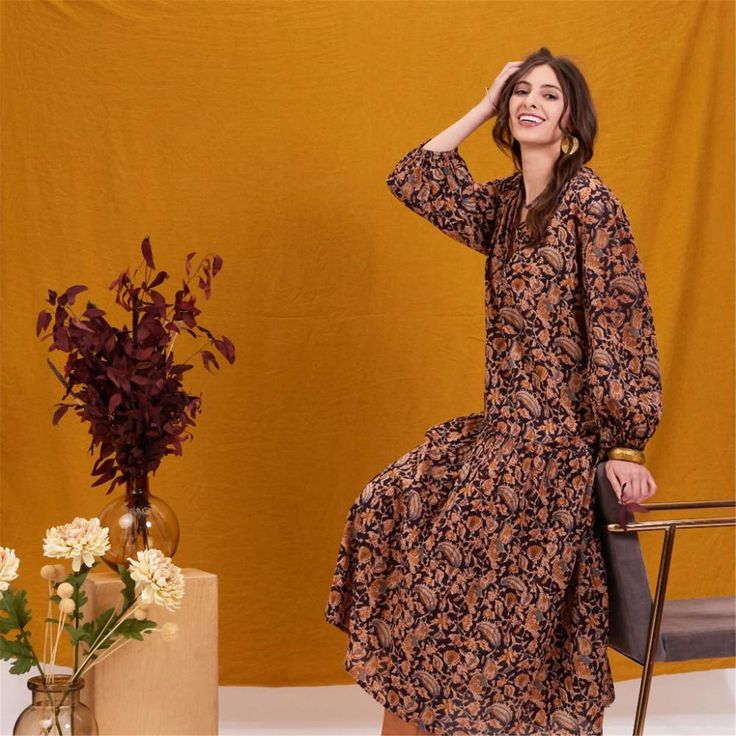 Add a splash of joy to your wardrobe with the Black Spice Madine Drop Waist Maxi Dress! Crafted from 100% cotton, this dress offers a delightfully comfortable fit that drapes beautifully. The vibrant pattern in warm spice tones is both eye-catching and stylish, perfect for making a statement. The full-length sleeves with elastic cuffs add a touch of charm and practicality, while the V-neck mandarin collar gives it an elegant touch. The dress features playful details like long decorative tassels Brown Relaxed Fit Dress For Fall, Flowy Cotton Maxi Dress For Fall, Brown Cotton Floral Print Dress, Fall Cotton Midi Dress With Floral Print, Fall Cotton Midi Dress In Brown, Brown Cotton Midi Dress For Fall, Decorative Tassels, Beach Towel Gift, Paper Cocktail Napkins