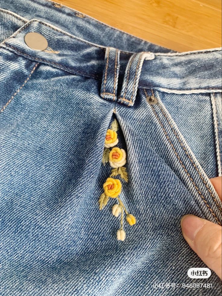 someone is stitching flowers on the back of their jeans