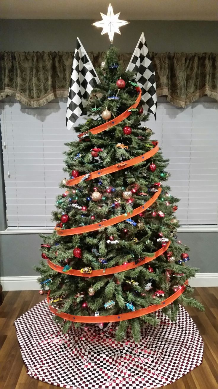 a decorated christmas tree with orange ribbon and ornaments on the top is in front of a window