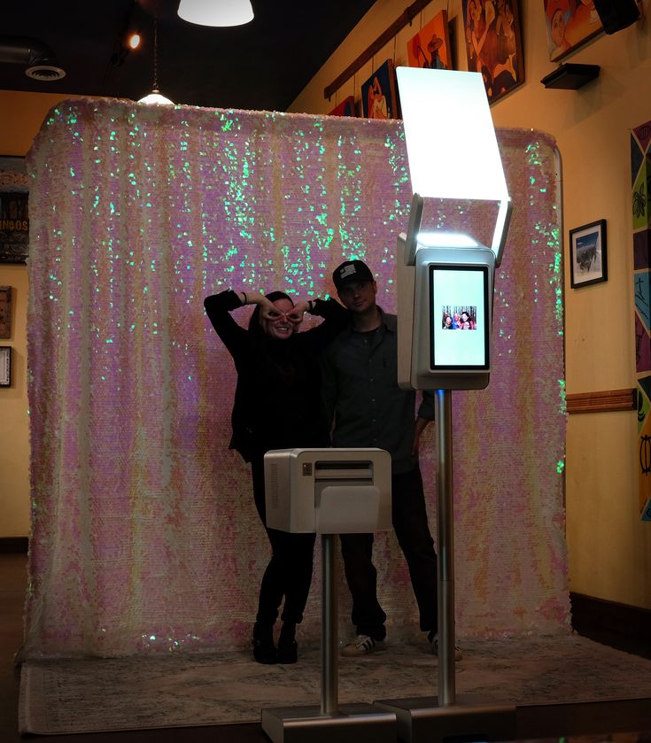 two people standing next to each other in front of a display with lights on it