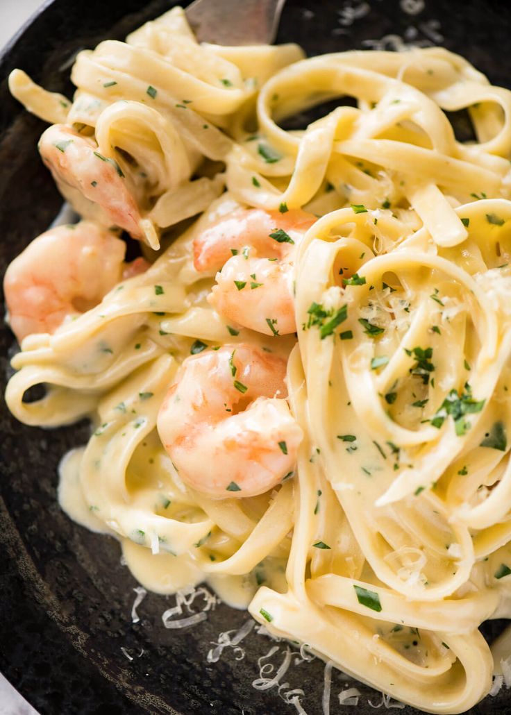 pasta with shrimp and parmesan cheese in a black bowl