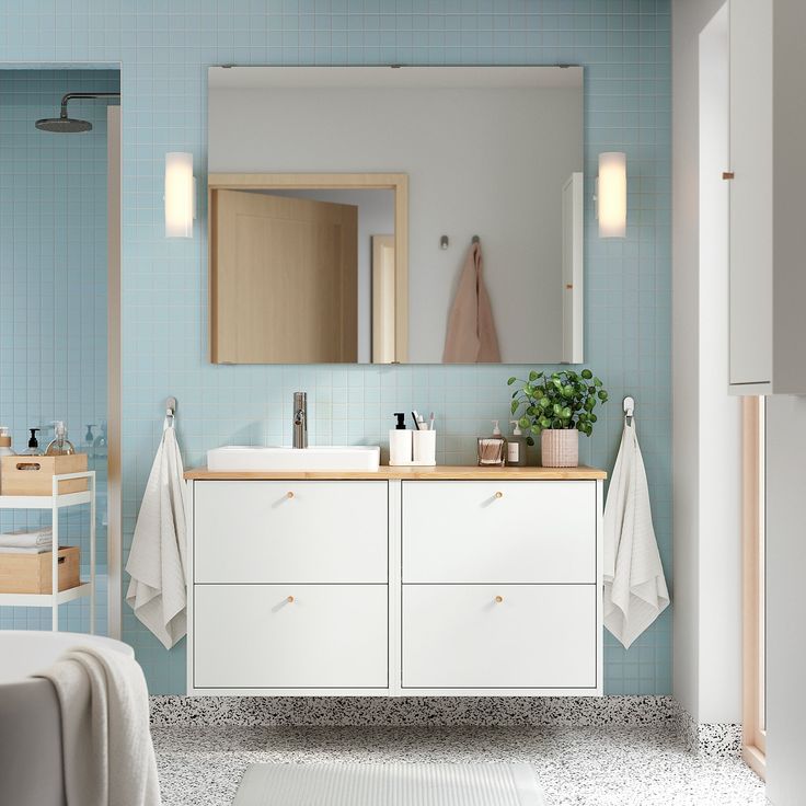 a bathroom with blue walls and white cabinets, including a large mirror over the sink