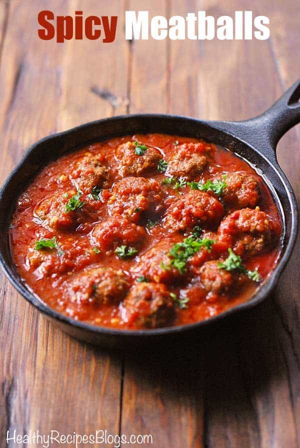 a skillet filled with meatballs on top of a wooden table