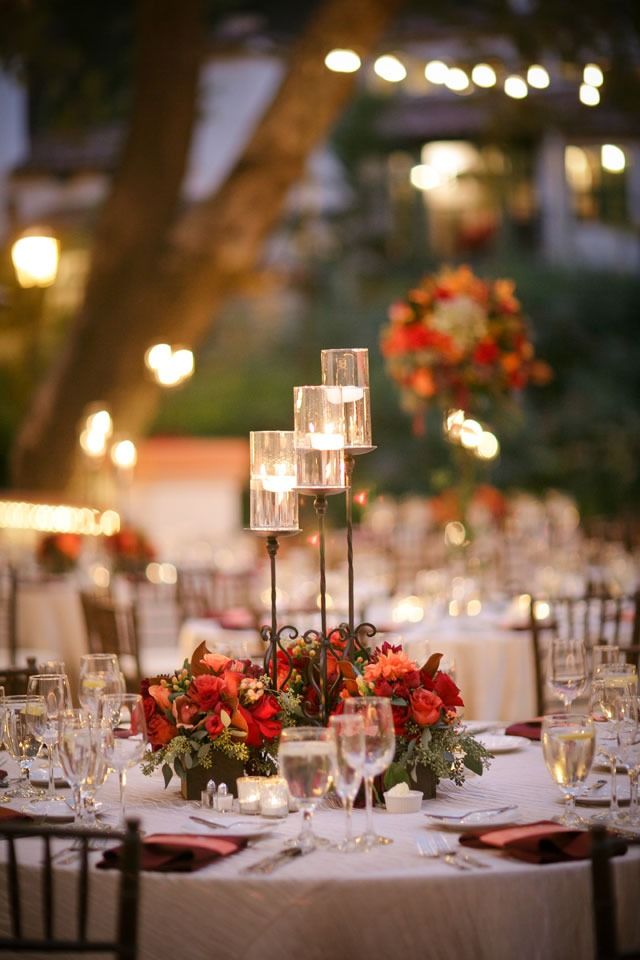 a table is set up with candles and flowers for an elegant wedding reception at the park