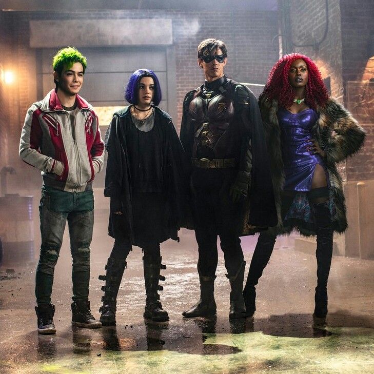 four people standing in front of a brick building with neon colored hair and costumes on