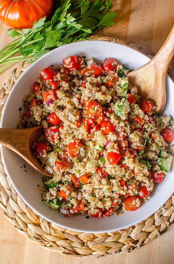 a white bowl filled with rice and tomatoes next to some vegetables on top of a wooden table