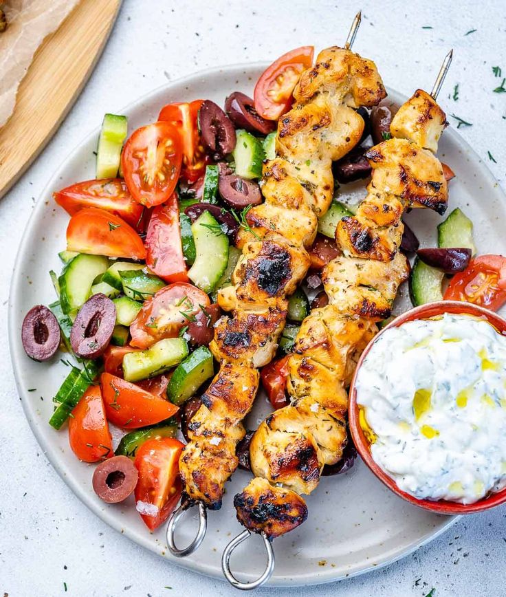 chicken kabobs with greek salad on a plate