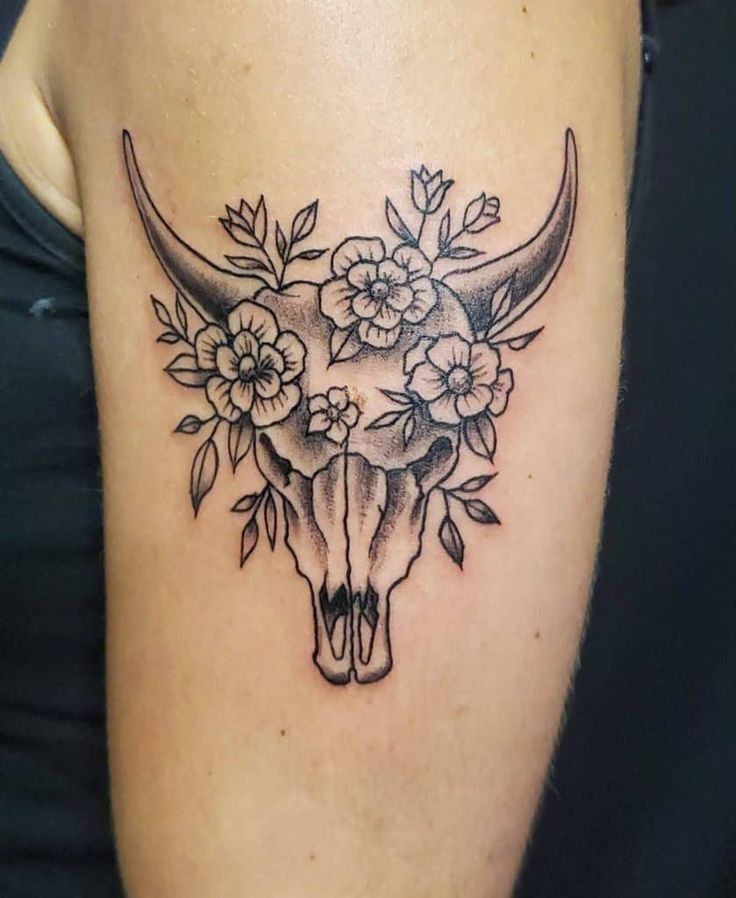 a bull skull with flowers on it's head is seen in this tattoo design