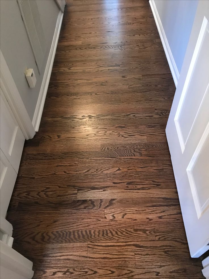 an empty hallway with wood floors and white trim