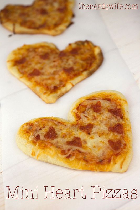 three heart shaped pizzas sitting on top of a white paper towel with the words, mini heart pizzas