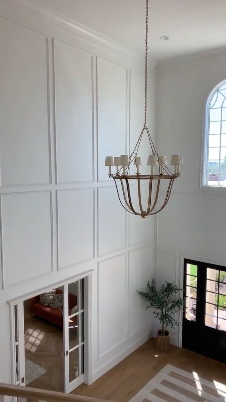 a chandelier hanging from the ceiling in a room with white walls and windows