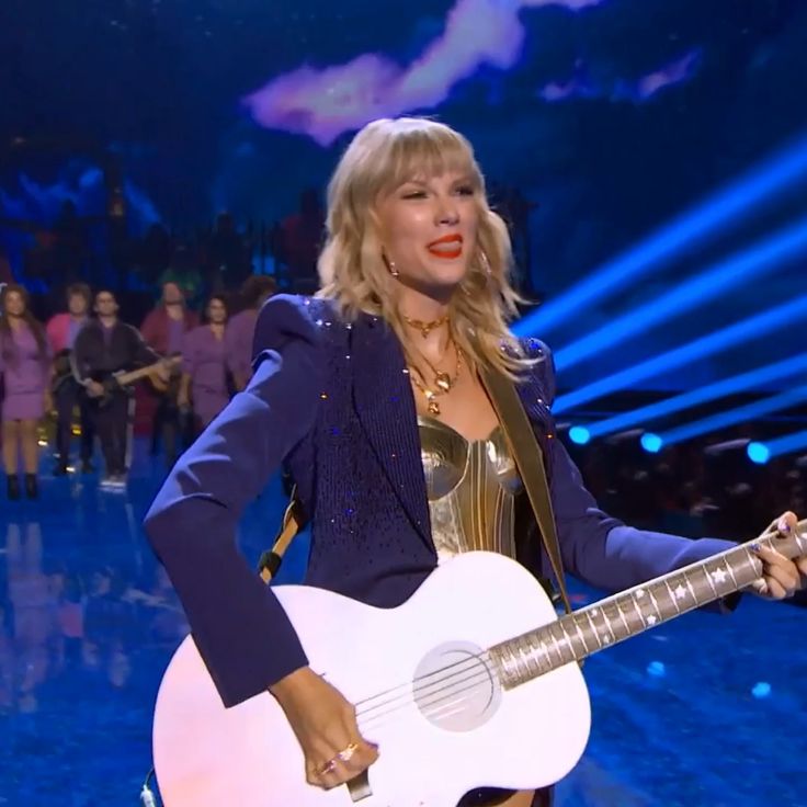 the woman is holding a guitar on stage