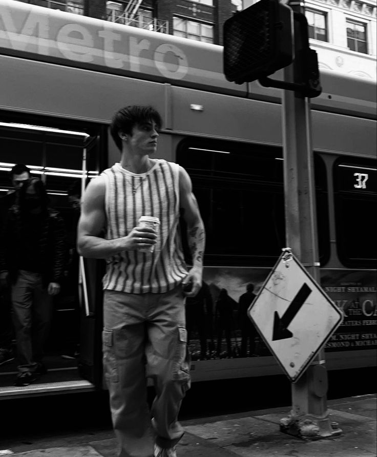 a man standing next to a bus on the side of the road near a traffic light