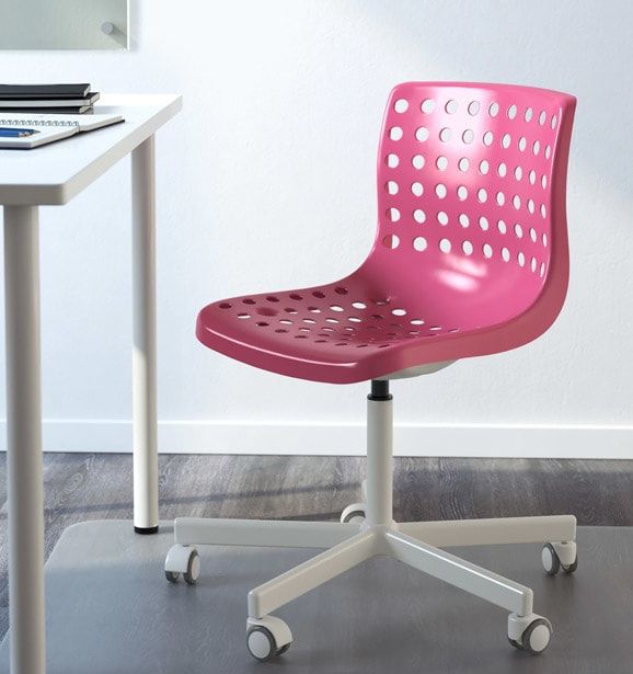 a pink office chair sitting on top of a metal table next to a white desk