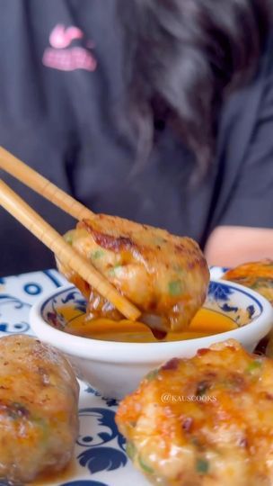 some food on a plate with chopsticks in it and a woman sitting at the table