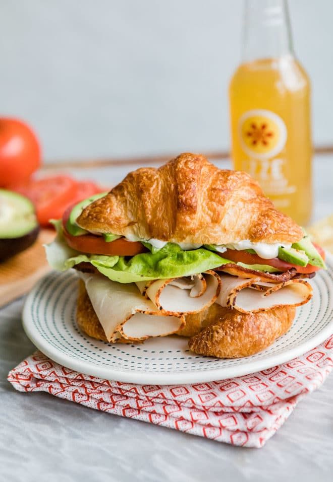 a sandwich sitting on top of a white plate next to a bottle of orange juice