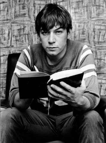 black and white photograph of a young man reading a book while sitting on a chair