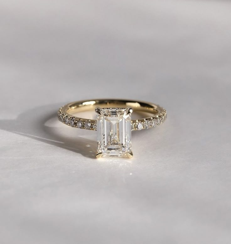 an emerald cut diamond engagement ring with pave diamonds