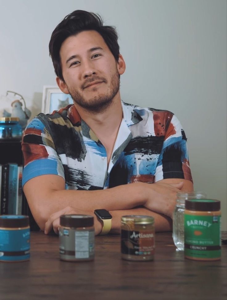 a man sitting at a table with some jars and cans in front of his face