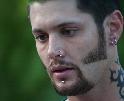 a man with piercings on his face and nose is looking at something in the distance