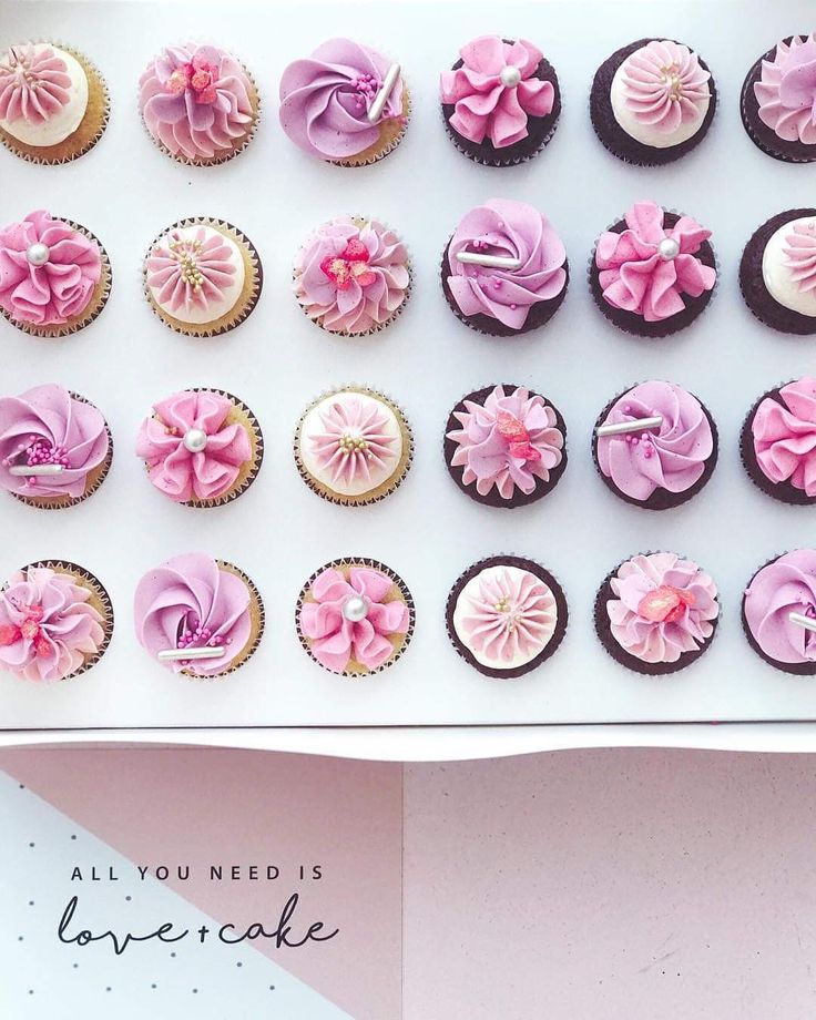 a box filled with lots of pink cupcakes on top of a white table