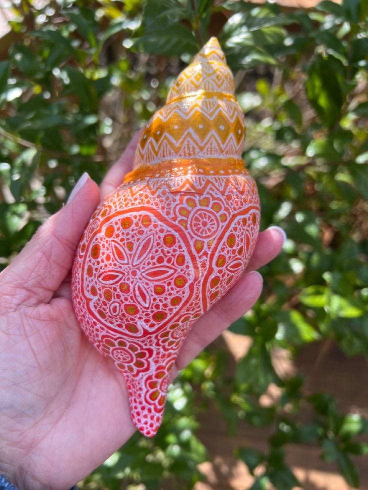 a hand holding an orange and yellow decorative object