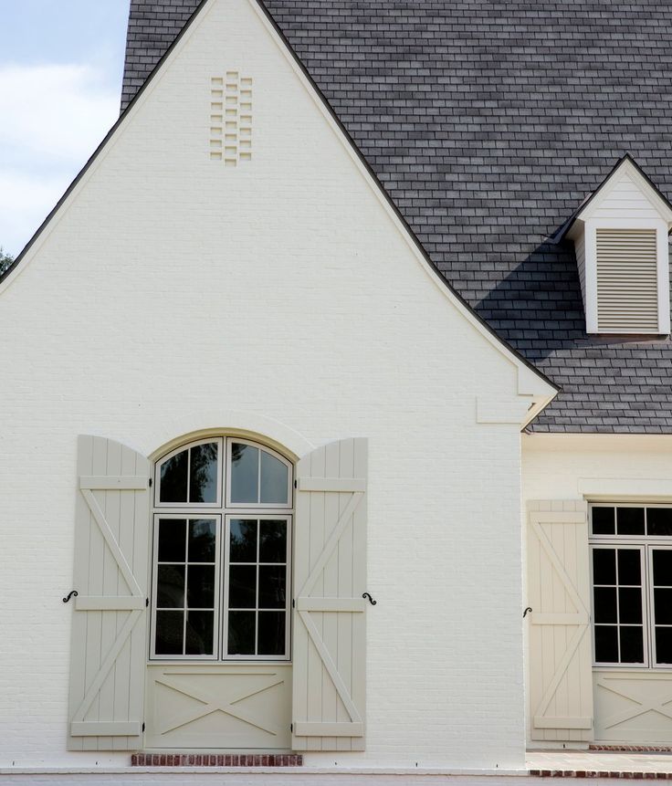 a white house with two windows and shutters