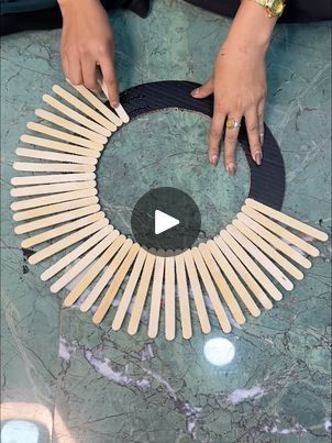 a woman is making a circle made out of wooden sticks and black leather banding