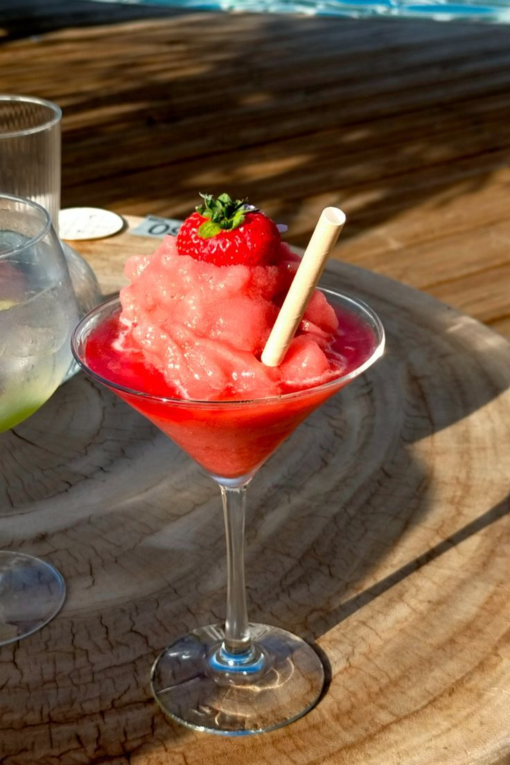 two glasses filled with ice cream and strawberries sitting on a table next to each other